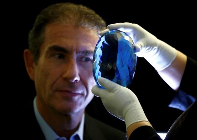 Philanthropist Maurice Ostro looks through his Ostro stone, the largest known blue topaz stone, for media at the Natural History Museum in London
